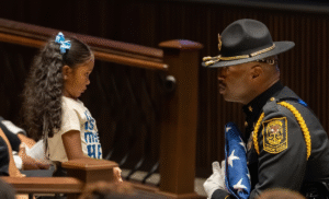 A police officer in dress uniform talking to a young girl at a formal ceremony.