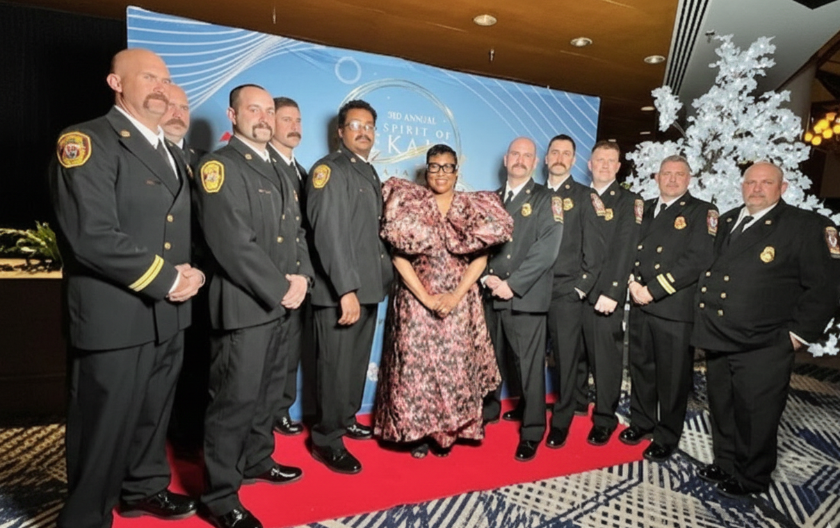 Lorraine Cochran-Johnson posing with a group of fire department officials in uniform.